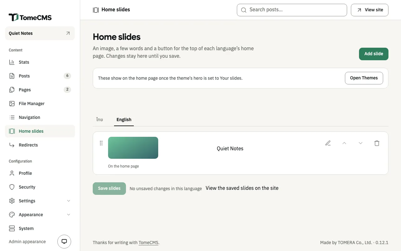 The Home slides screen. A notice says the slides show once the theme’s hero is set to Your slides, beside “Open Themes”. Below, the “English” tab is chosen and holds one slide, a green picture with the heading “Quiet Notes”, marked “On the home page”. Under the list are “Save slides”, “No unsaved changes in this language” and “View the saved slides on the site”.